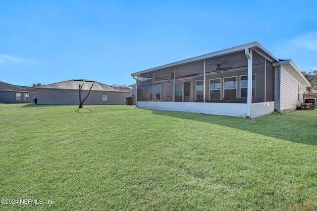 rear view of house with a sunroom, central air condition unit, and a lawn