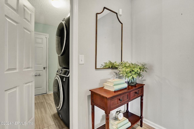 laundry room featuring a textured ceiling, light hardwood / wood-style floors, and stacked washer and clothes dryer