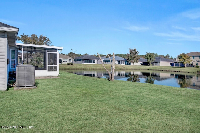 view of yard with a sunroom, a water view, and central AC unit