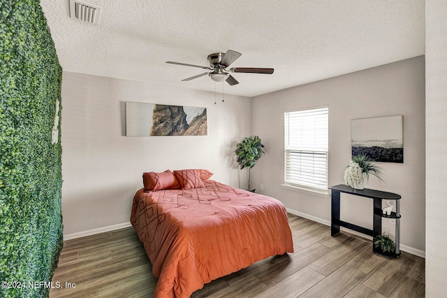 bedroom with a textured ceiling, hardwood / wood-style flooring, and ceiling fan