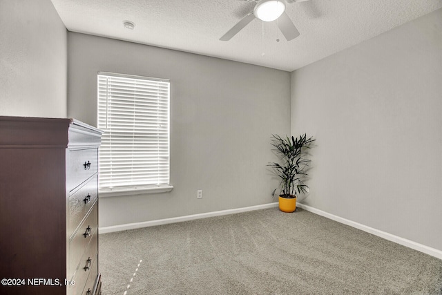 spare room featuring carpet flooring, ceiling fan, and a textured ceiling