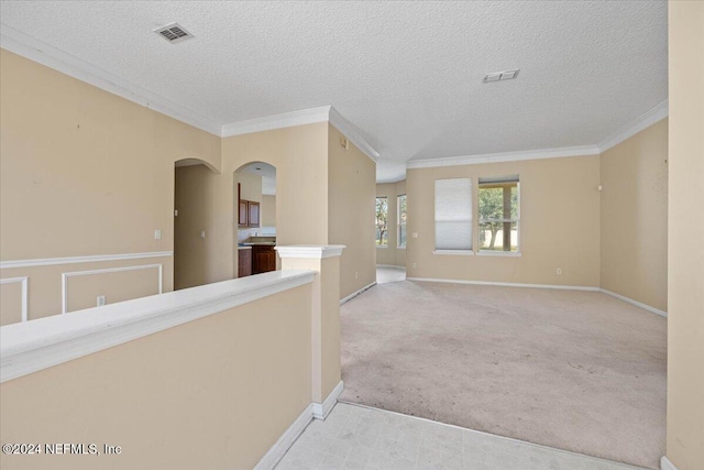 corridor featuring light carpet, a textured ceiling, and crown molding