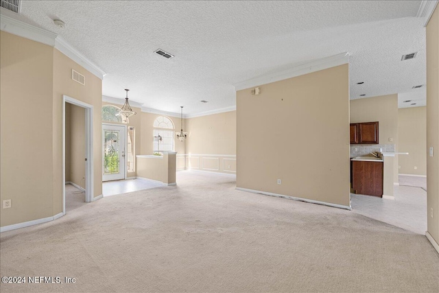 empty room featuring light carpet, a textured ceiling, crown molding, and a notable chandelier