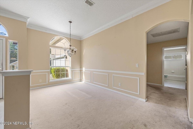 empty room with an inviting chandelier, light colored carpet, a textured ceiling, and ornamental molding