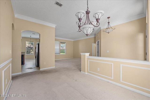 carpeted spare room with crown molding, a chandelier, and a textured ceiling