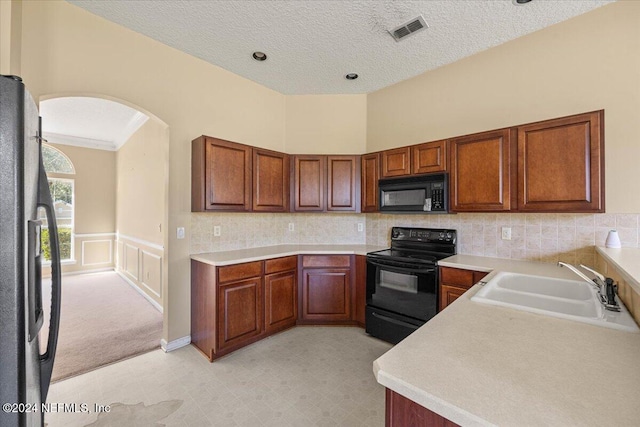 kitchen featuring a textured ceiling, sink, backsplash, and black appliances