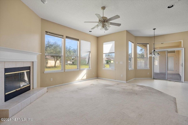 unfurnished living room featuring a textured ceiling, ceiling fan with notable chandelier, and a fireplace