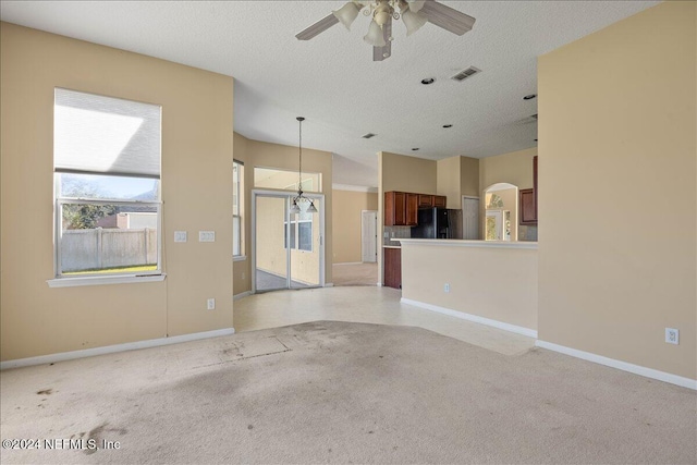 unfurnished living room featuring ceiling fan, a textured ceiling, and light carpet