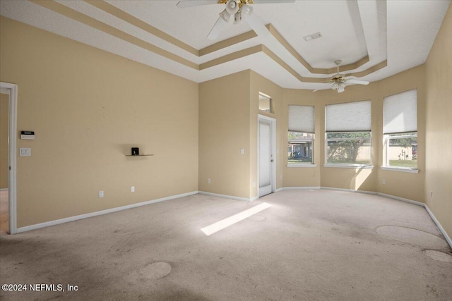 carpeted empty room featuring ceiling fan and a tray ceiling