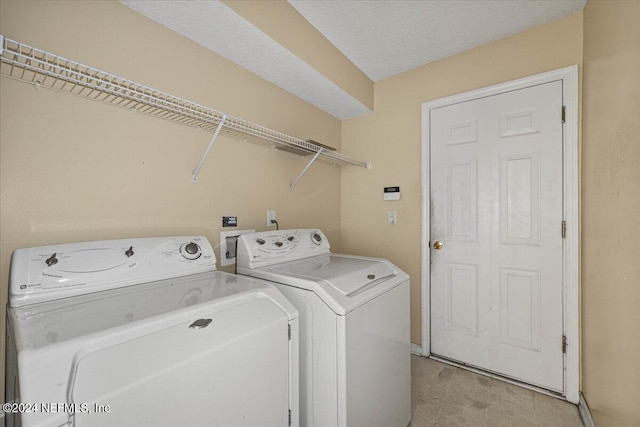 laundry area with washing machine and dryer and a textured ceiling