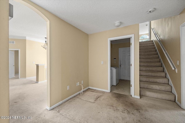 stairway featuring carpet, washing machine and dryer, and a textured ceiling