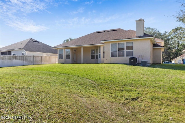 back of house with central air condition unit and a yard