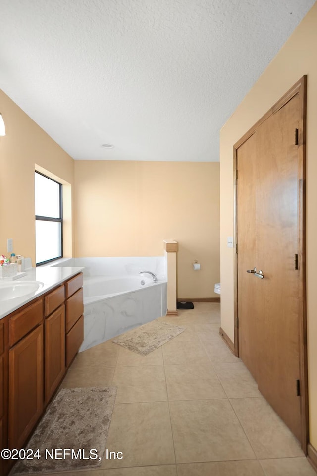 bathroom featuring a tub to relax in, tile patterned floors, vanity, a textured ceiling, and toilet