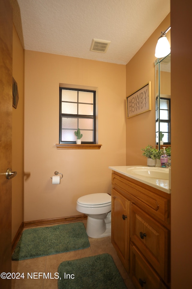 bathroom with tile patterned floors, vanity, toilet, and a textured ceiling