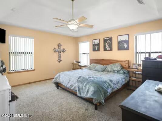 carpeted bedroom with ceiling fan and multiple windows