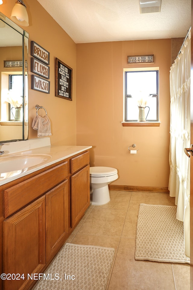 bathroom with tile patterned floors, vanity, a textured ceiling, and toilet