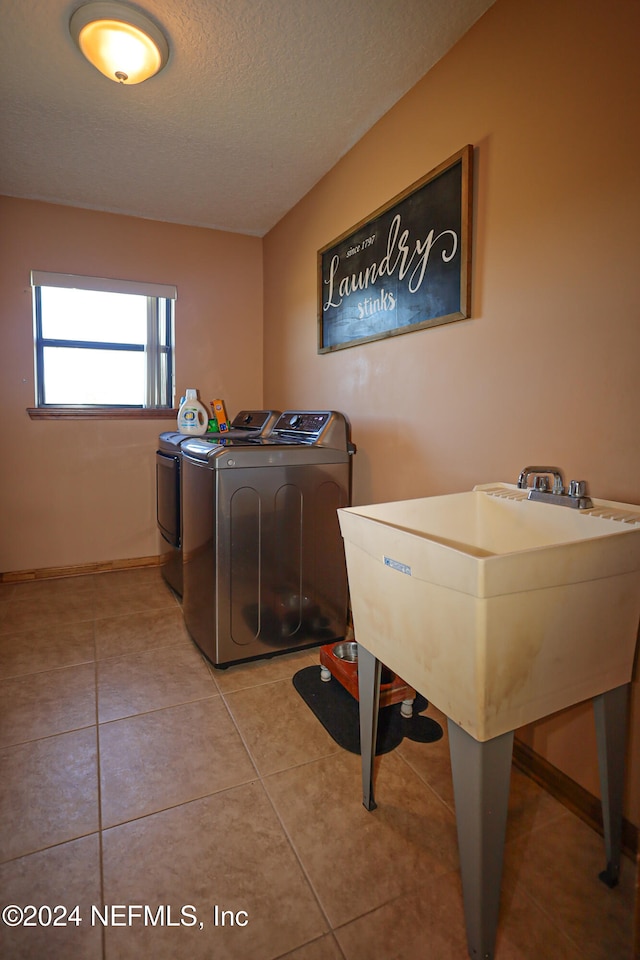 laundry area featuring washing machine and dryer, light tile patterned floors, and a textured ceiling