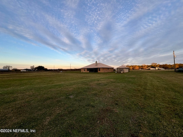 yard at dusk featuring a rural view