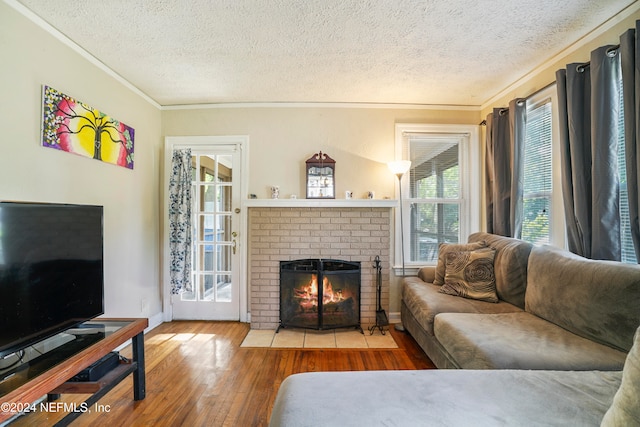 living room with a fireplace, hardwood / wood-style floors, a textured ceiling, and ornamental molding