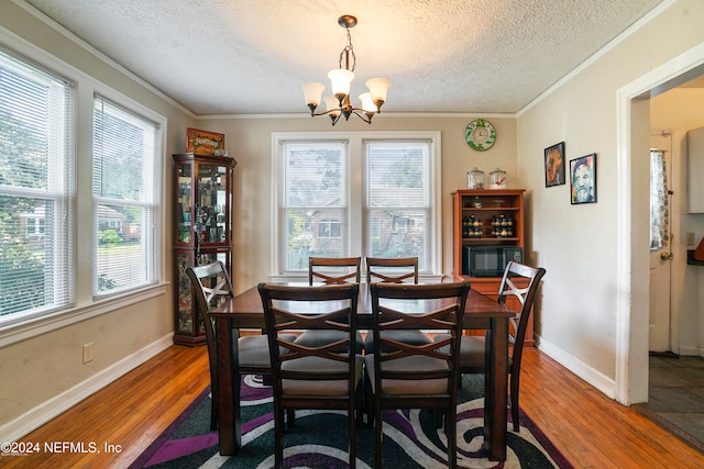 dining space with a wealth of natural light, hardwood / wood-style floors, and an inviting chandelier