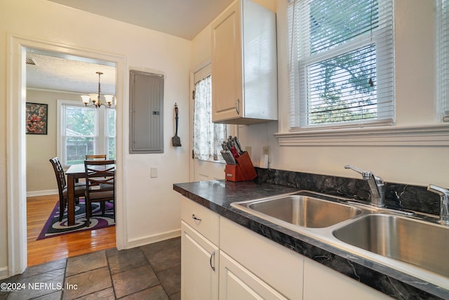 kitchen with white cabinets, a notable chandelier, sink, and electric panel