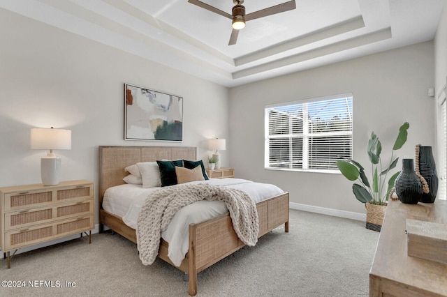 carpeted bedroom featuring ceiling fan and a raised ceiling