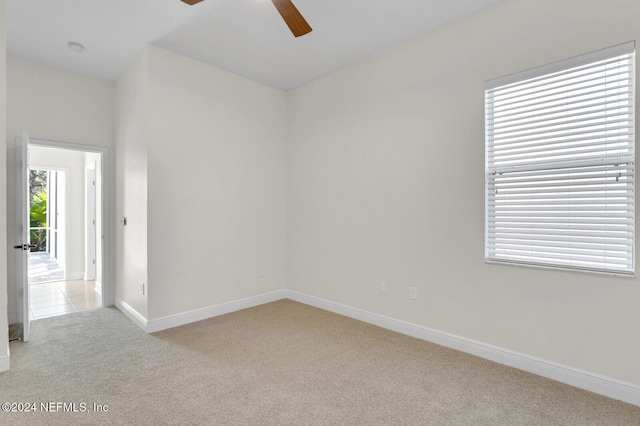 empty room featuring ceiling fan and light colored carpet