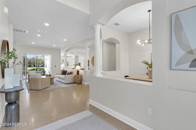 corridor featuring light tile patterned floors, decorative columns, and a notable chandelier