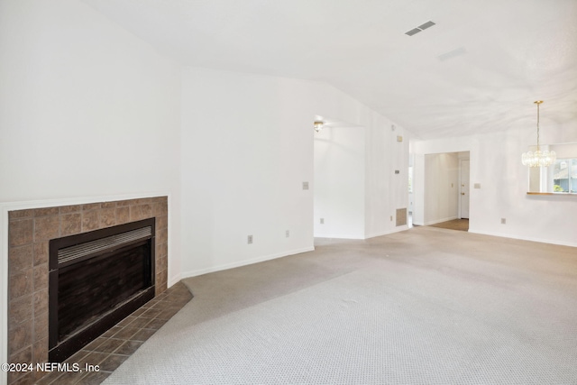 carpeted living room featuring a notable chandelier, lofted ceiling, and a tiled fireplace