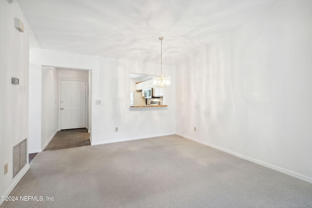 carpeted empty room featuring a chandelier