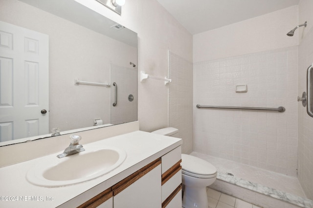 bathroom with a tile shower, tile patterned flooring, vanity, and toilet