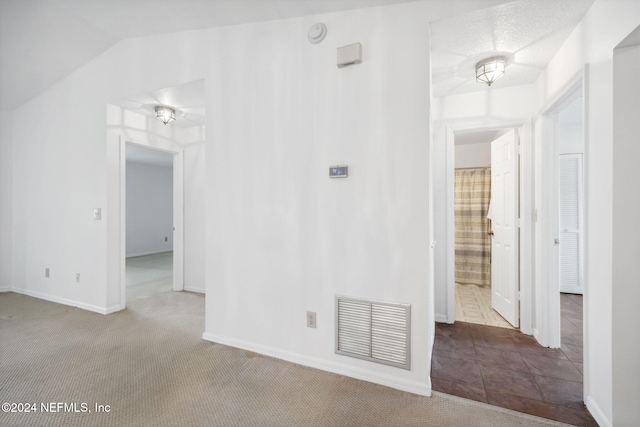 empty room featuring carpet flooring and vaulted ceiling