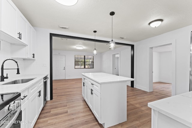 kitchen with stainless steel appliances, white cabinetry, light hardwood / wood-style floors, and sink