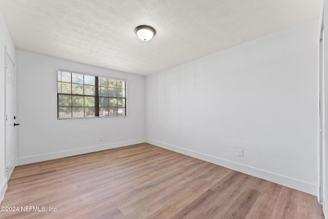 spare room featuring a textured ceiling and light wood-type flooring