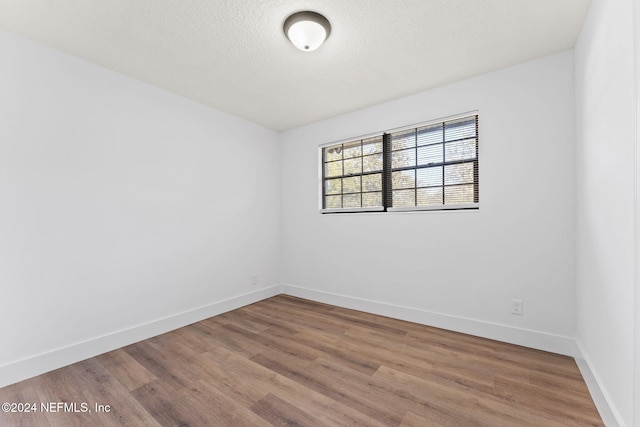 empty room with hardwood / wood-style floors and a textured ceiling