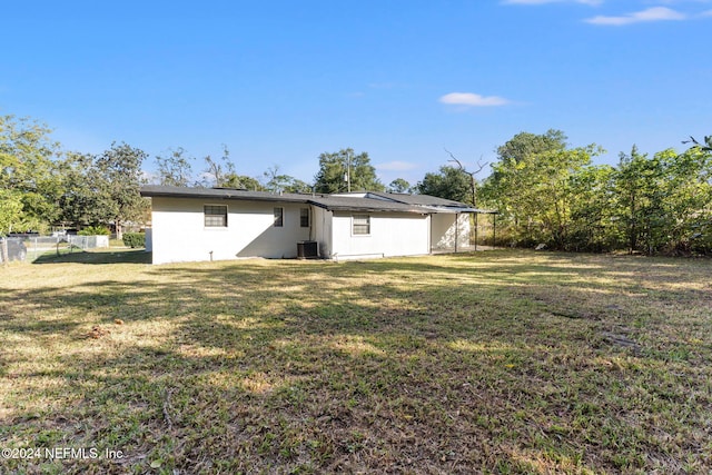 rear view of house featuring a yard and central AC