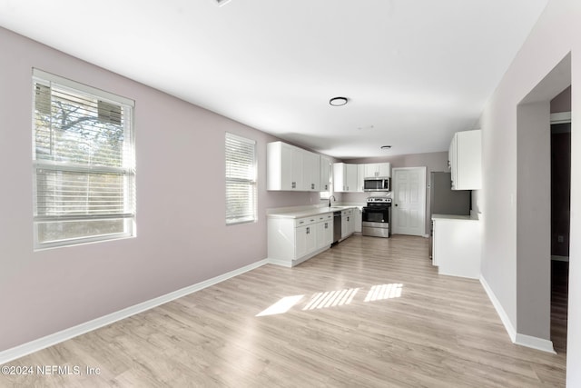 kitchen with white cabinets, stainless steel appliances, plenty of natural light, and light hardwood / wood-style floors