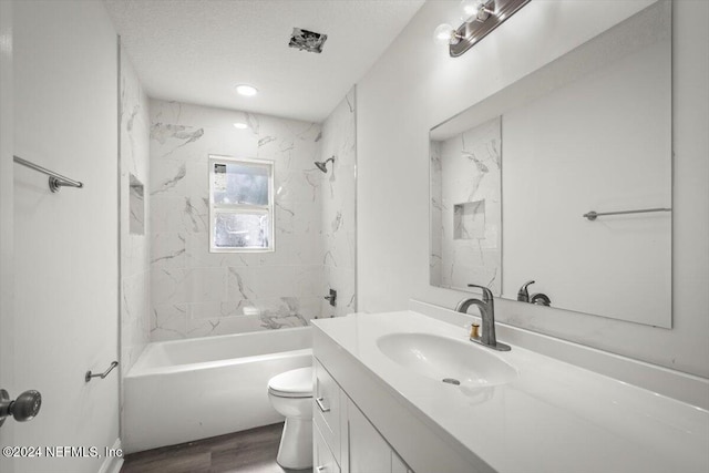 full bathroom featuring hardwood / wood-style floors, vanity, tiled shower / bath, toilet, and a textured ceiling