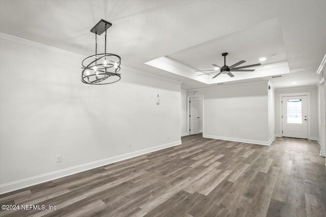 unfurnished living room with ceiling fan with notable chandelier, a raised ceiling, crown molding, hardwood / wood-style flooring, and a textured ceiling