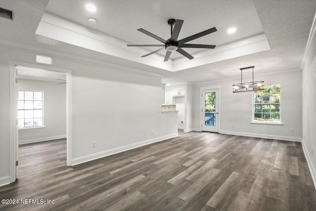 unfurnished living room featuring a textured ceiling, ceiling fan with notable chandelier, dark hardwood / wood-style floors, and ornamental molding