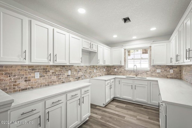 kitchen featuring white cabinets, light hardwood / wood-style floors, sink, and a textured ceiling