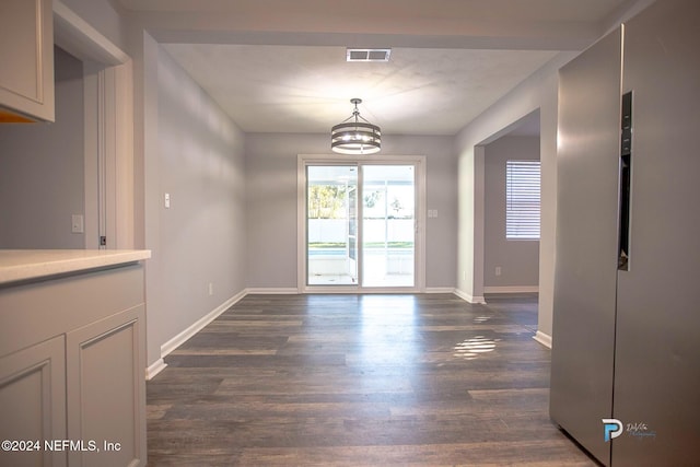 unfurnished dining area featuring dark hardwood / wood-style flooring and an inviting chandelier