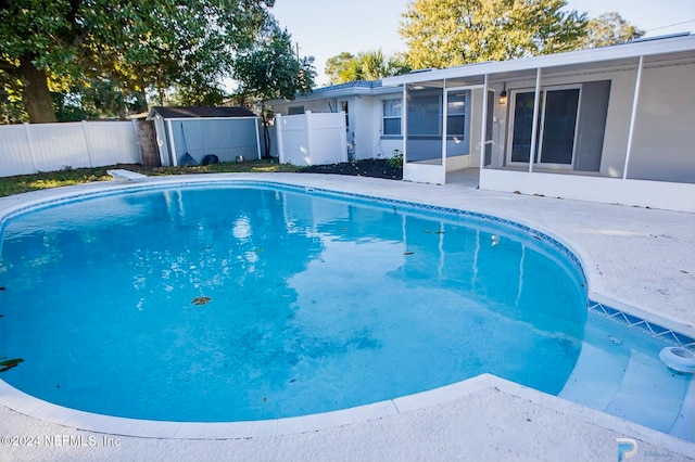 view of swimming pool featuring a sunroom and a storage unit