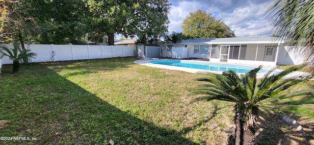 view of pool with a sunroom, a storage shed, and a yard