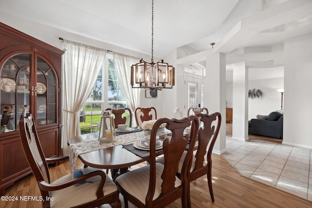 dining space featuring a chandelier, light wood-type flooring, and vaulted ceiling