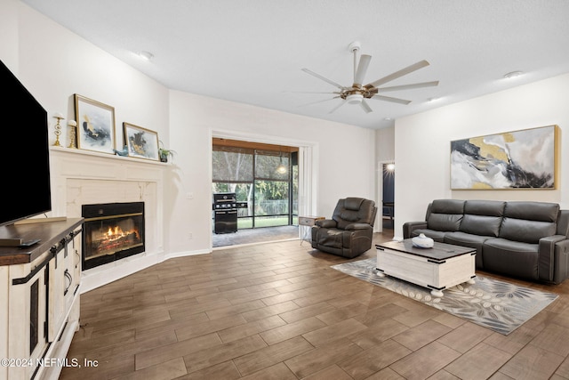 living room with dark hardwood / wood-style floors, ceiling fan, and a premium fireplace