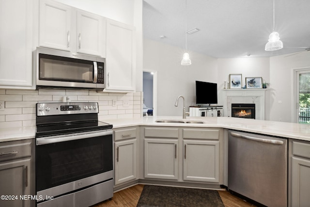 kitchen featuring a fireplace, sink, stainless steel appliances, and decorative light fixtures