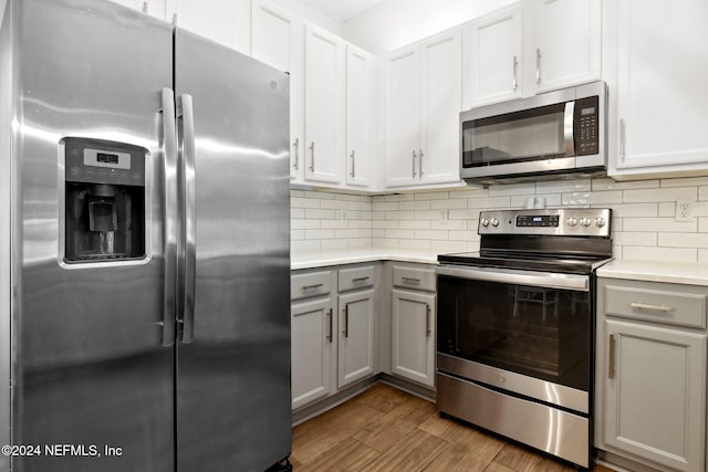 kitchen featuring gray cabinetry, white cabinetry, backsplash, appliances with stainless steel finishes, and light wood-type flooring