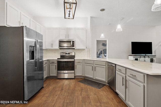 kitchen featuring sink, decorative light fixtures, dark hardwood / wood-style flooring, kitchen peninsula, and stainless steel appliances