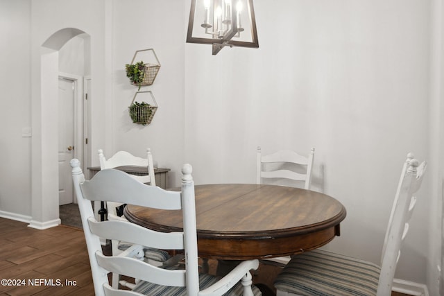 dining space with dark wood-type flooring and an inviting chandelier